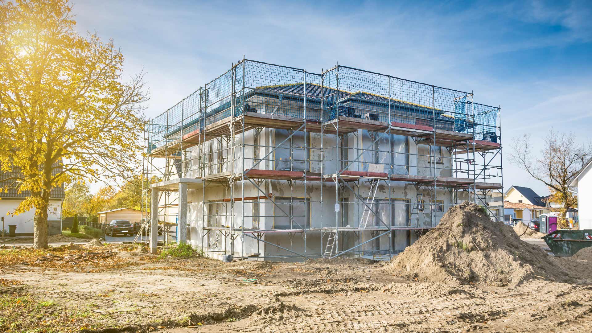 Ein modernes Haus im Rohbau mit Gerüst, hellem Anstrich und sonnigem Herbsttag