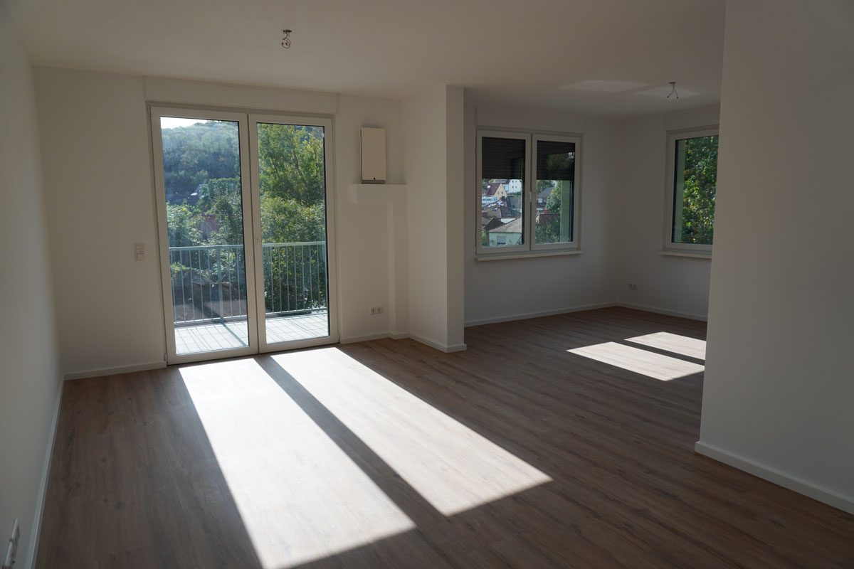 Bright living room with large windows, hardwood floors, and a view of the greenery