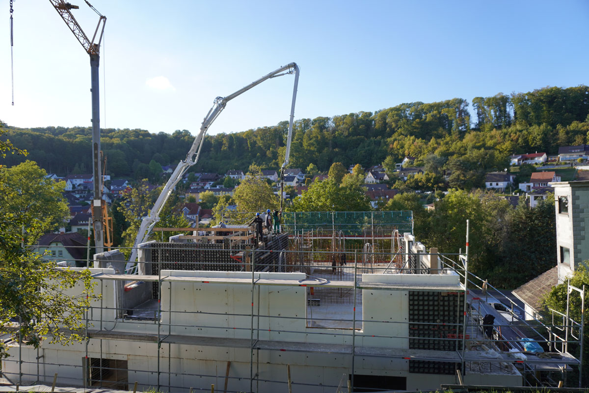 Several construction workers are working intently on a construction site with cranes and scaffolding