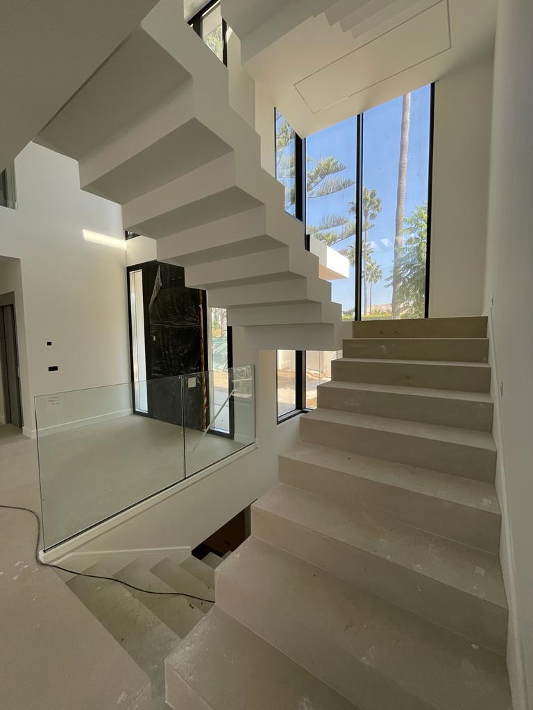 A bright, modern stairwell with large glass windows and cantilevered steps