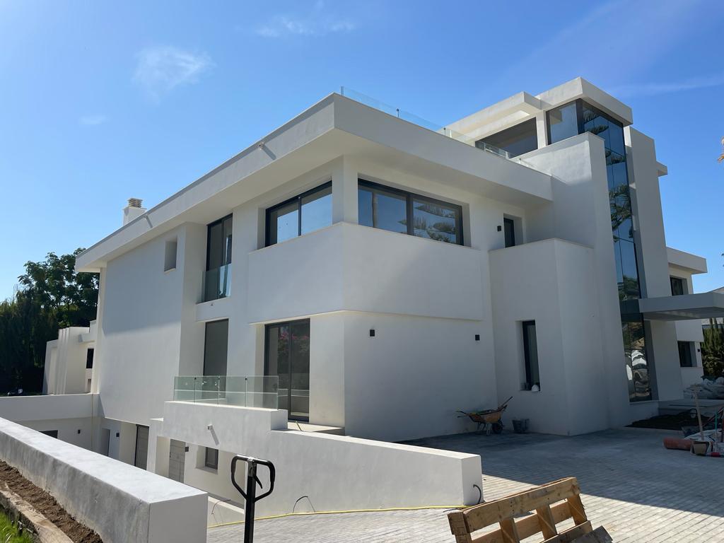 Modern white house with large windows, a glass balcony, and clean lines
